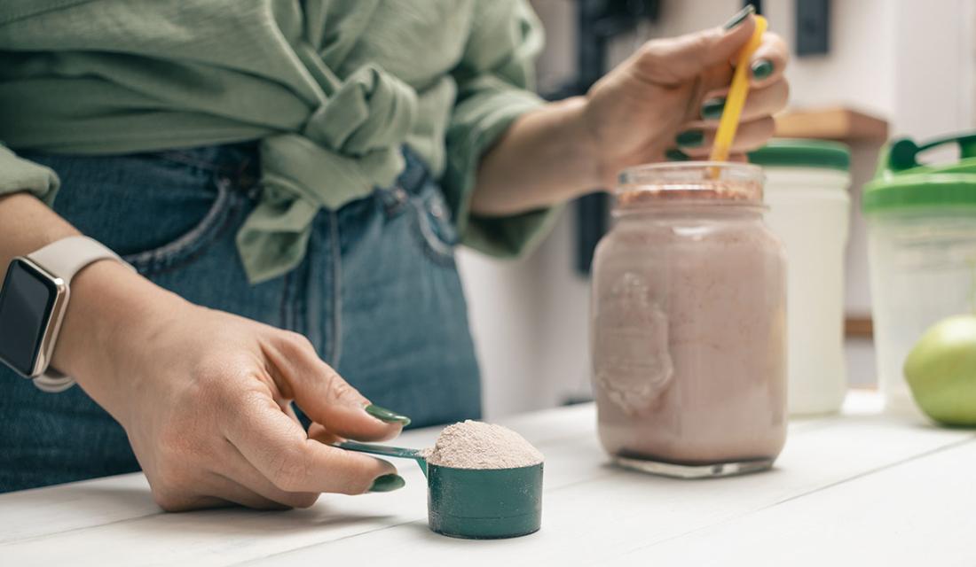 Frau bereitet einen Shake aus Proteinpulver zu