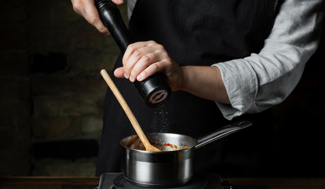 Pfeffer wird aus Mühle in den Topf gegeben