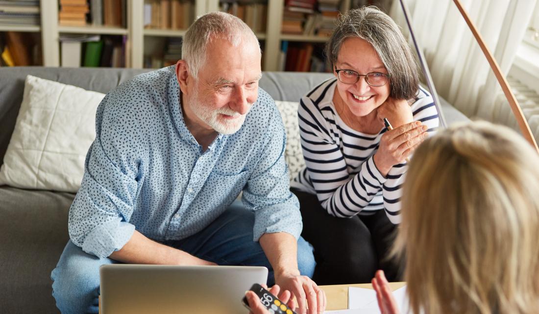 Paar sitzt mit Beraterin am Tisch mit Laptop und Taschenrechner