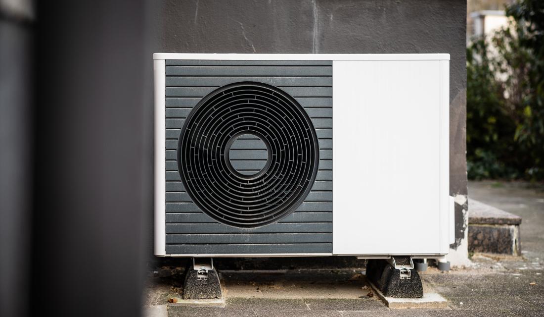 Eine Wärmepumpe steht vor einer Hauswand