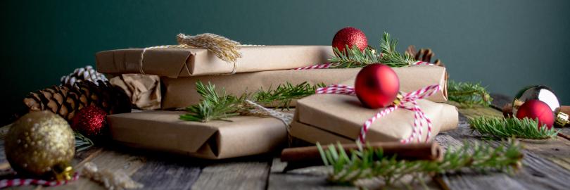 Weihnachtsgeschenke, die in Packpapier verpackt sind sowie Weihnachtskugeln und Tannen