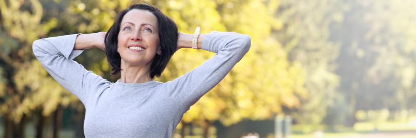 Eine Frau über 50 stretcht sich beim Sport in einem Park
