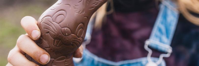 Mädchen hält angebissenen Schoko-Osterhasen