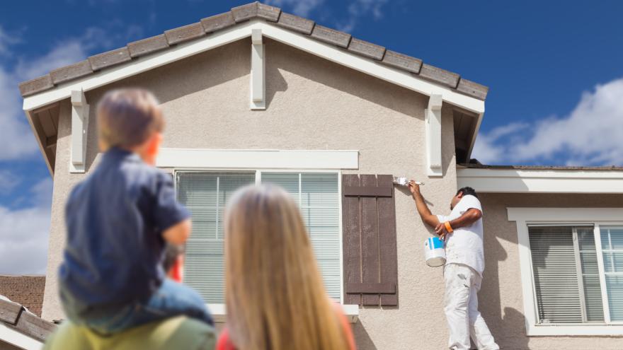 Eine Familie sieht einem Handwerker bei Arbeiten an Ihrem Haus zu