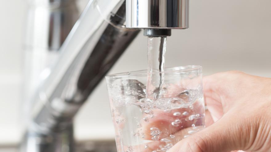 Mann schenkt Glas Leitungswasser ein