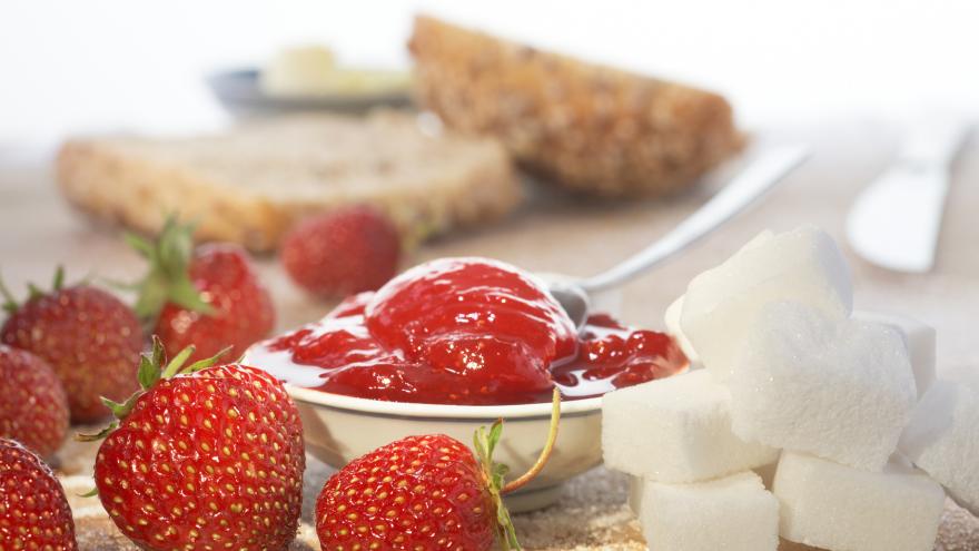 Frühstückstisch mit Erdbeeren, Marmelade und Zuckerwürfeln