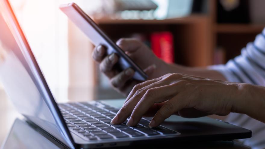Frau am Computer mit Smartphone