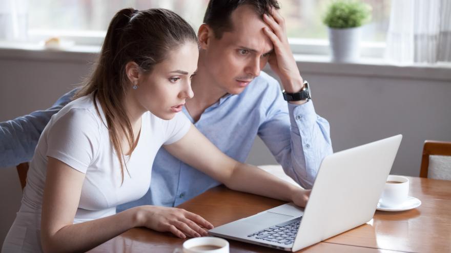 Paar sitzt mit empörtem Gesichtsausdruck vor einem Laptop