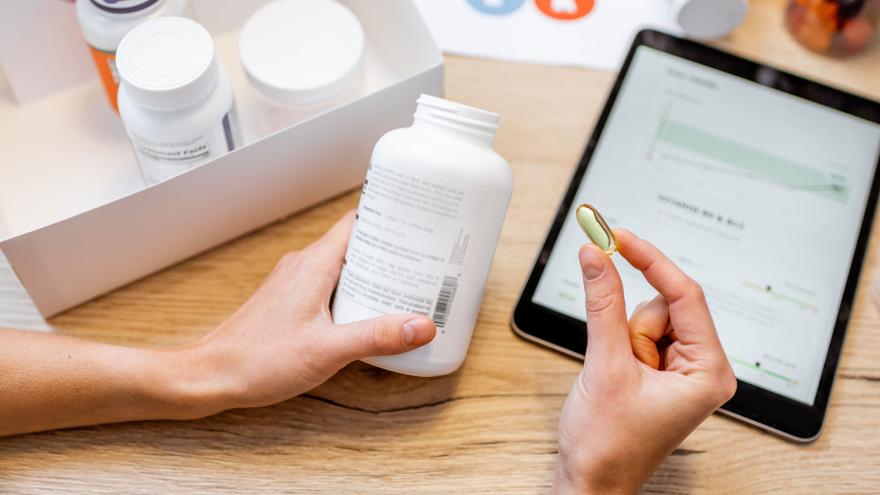 Frau betrachtet Pillendose und Pille