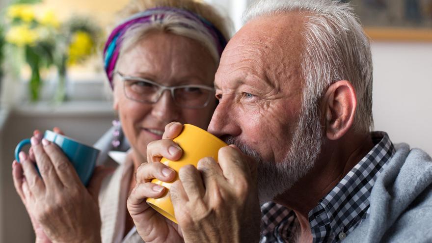 Senioren sitzen und trinken aus den großen Tassen