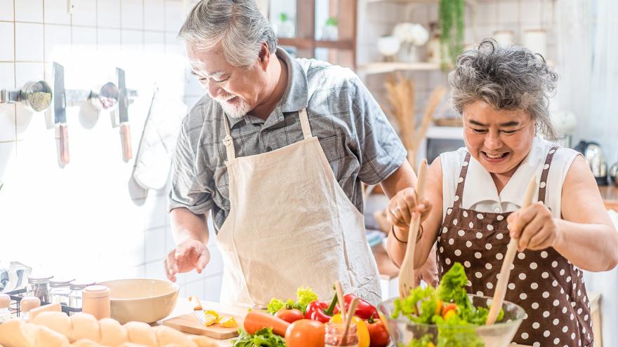Senioren aus Asien kochen zusammen in der Küche gesund