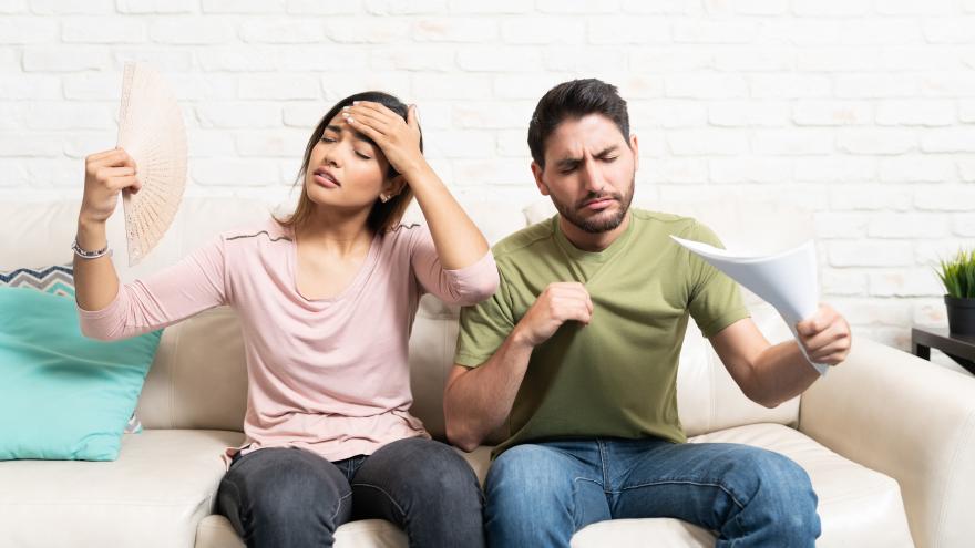 Paar sitzt auf einer Couch und fächert sich Luft zu