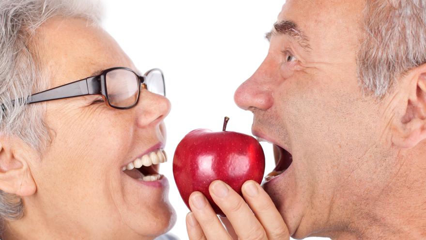 Älteres Paar beißt genussvoll in einen Apfel
