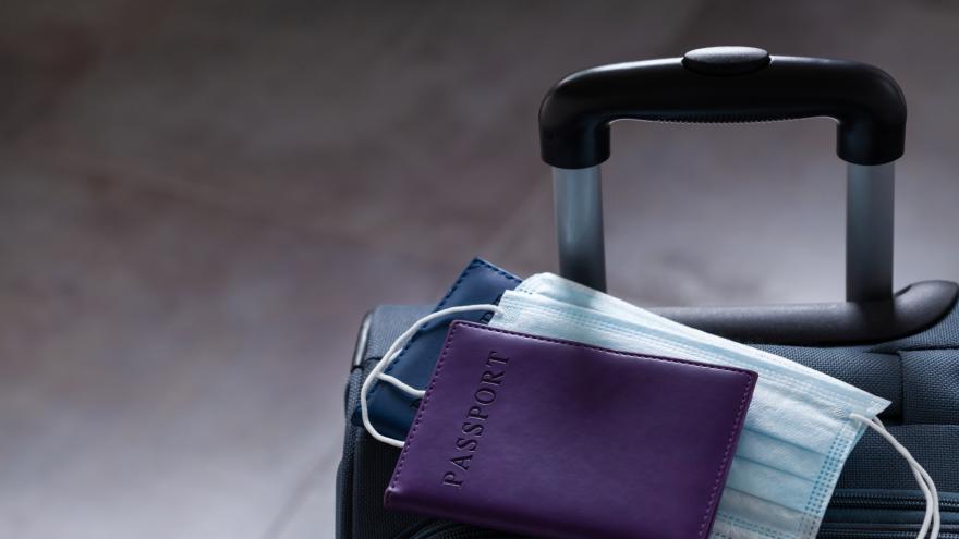 Pass und medizinische Gesichtsmaske liegen auf einem Reisekoffer