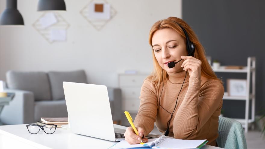 Frau mit Headset sitzt am Schreibtisch vor einem Laptop