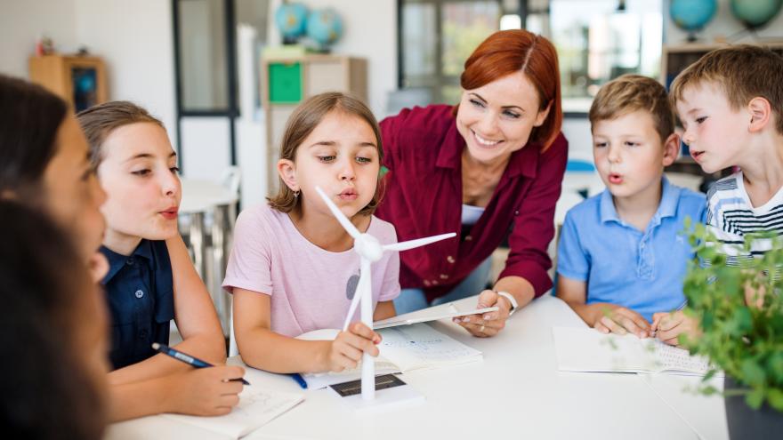 Lehrerin beim Erklären einer Windkraftanlage mit einer Gruppe Kinder