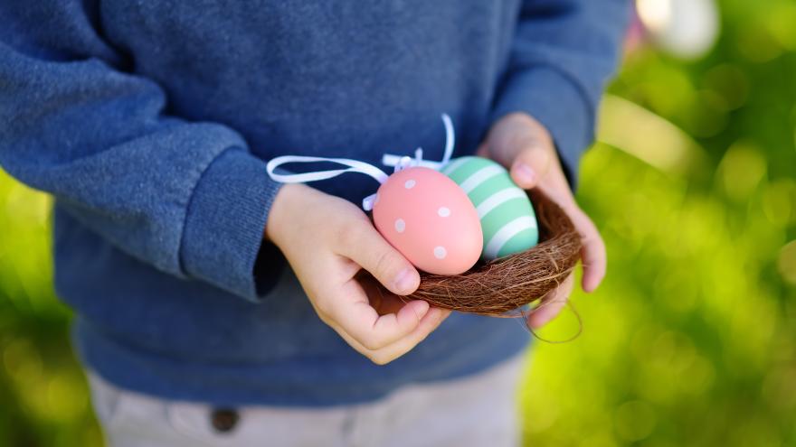 Junge im Garten trägt einen Korb mit Ostereiern
