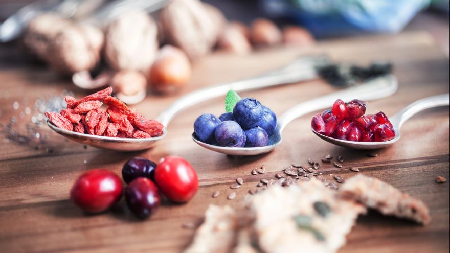 Goji Beeren, Acai Berren und andere sogenannte Superfoods liegen in einem Löffel auf einer hölzernen Arbeitsplatte