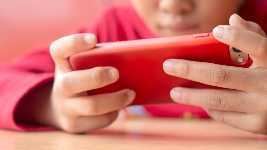 Kind beim Spielen mit einem roten Smartphone