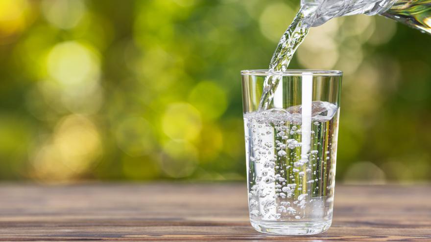 Wasser wird aus einer Karaffe in ein Glas eingeschenkt