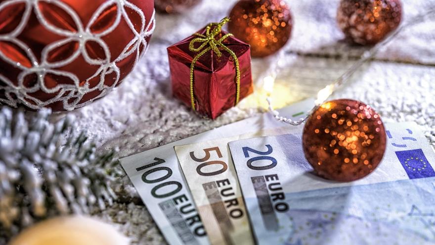 Eine Christbaumkugel liegt auf Euro-Scheinen um Weihnachtsgeld darzustellen