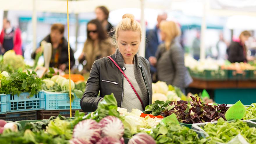 Frau beim Gemüseeinkauf an einem Marktstand