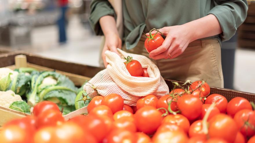 Eine Frau packt Tomaten in ein Stoffsäckchen.