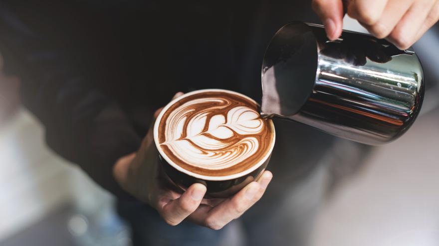 Ein Mann schüttet Milch in den Kaffee.