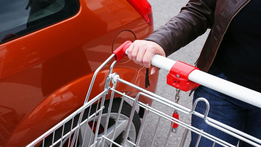 Jemand schiebt einen Einkaufswagen vom Auto weg.