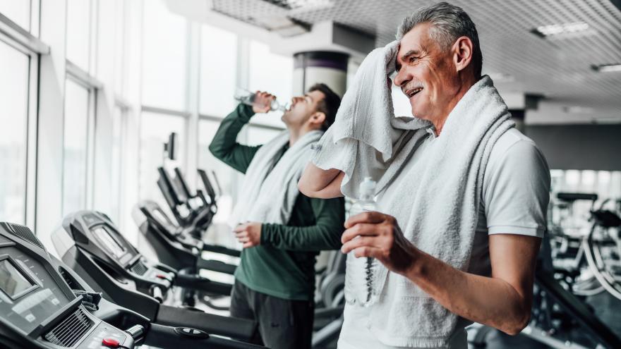 Mann im Fitnessstudio wischt sich mit einem Handtuch die Stirn ab