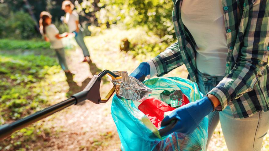 Frau mit Müllbeutel beim Aufräumen eines Parks