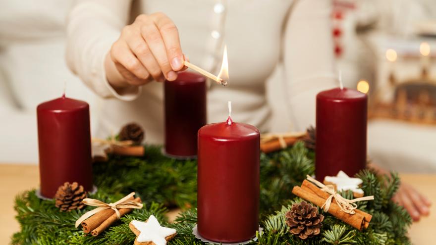 Eine Frau zündet Kerzen am Adventskranz an.