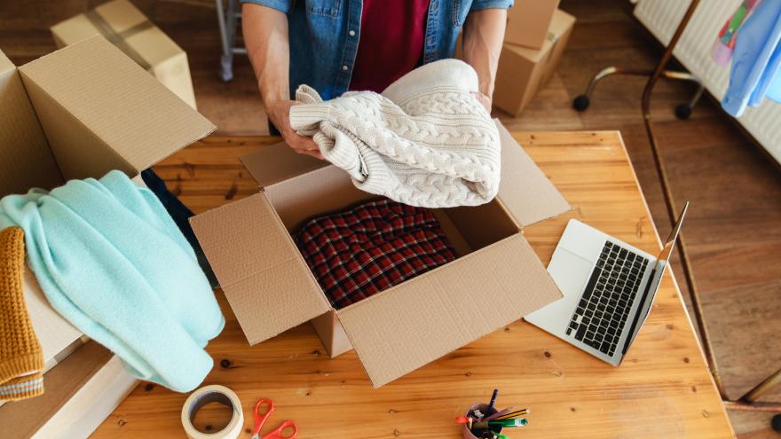 Kleidung wird in einen Karton gepackt.