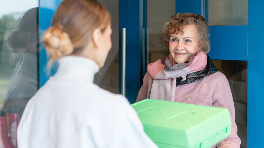 Seniorin empfängt eine Essenslieferung an der Tür