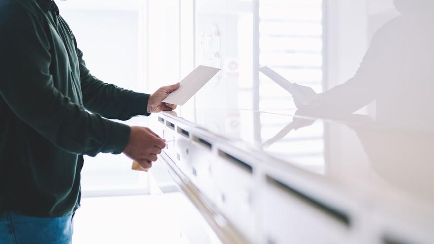 Mann holt Post aus Briefkasten