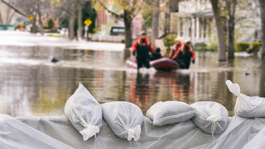 Sandsackbarriere vor überschwemmter Straße mit Schlauchboot