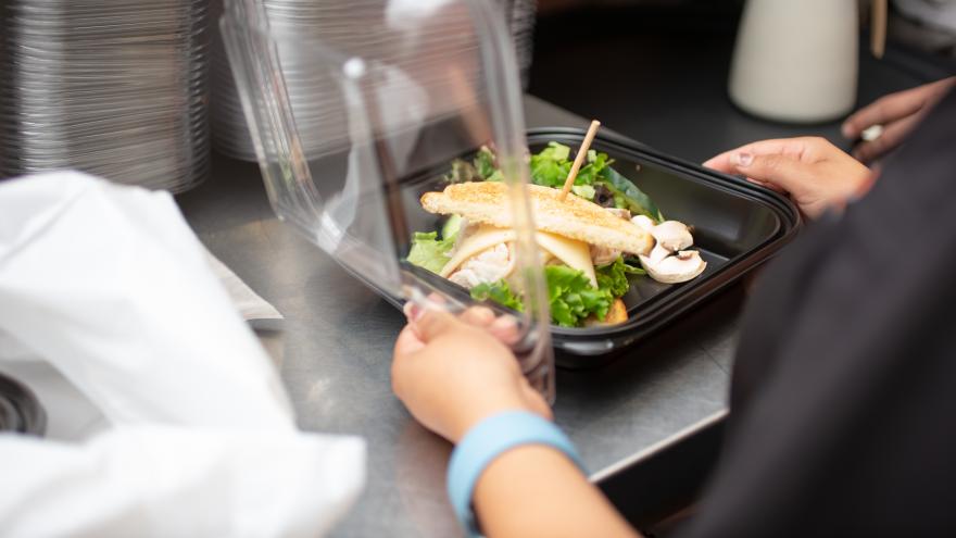 Frau verpackt Essen für einen Lieferdienst in einem Einwegbehälter