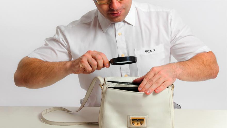Mann von der Security untersucht Tascheninhalt
