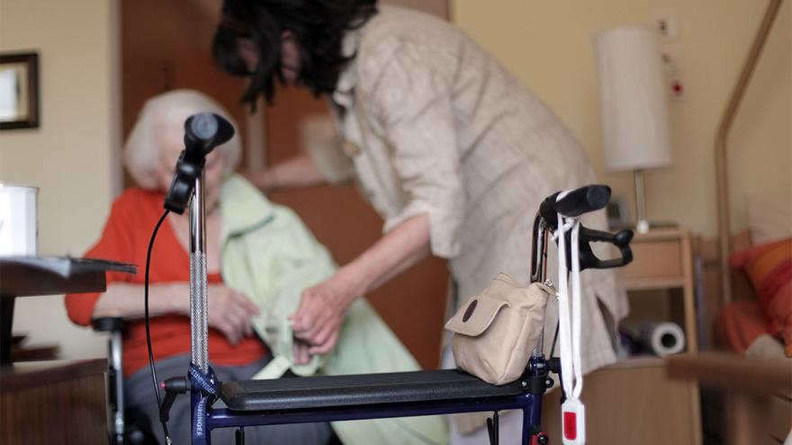 Rollator steht vor Seniorin und Pflegerin