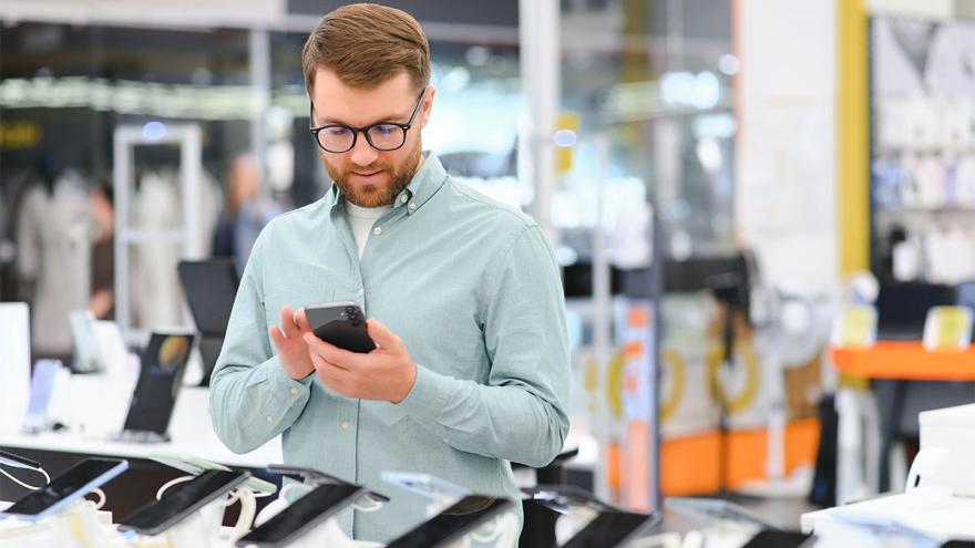 Mann sucht Smartphone in Elektronikmarkt aus