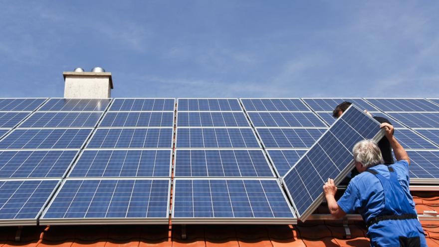 Eine PV-Anlage wird auf einem Dach von Monteuren installiert