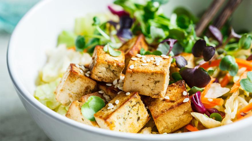 Schüssel mit Tofu-Salat. Im Hintergrund ragen Essstäbchen aus der Schüssel