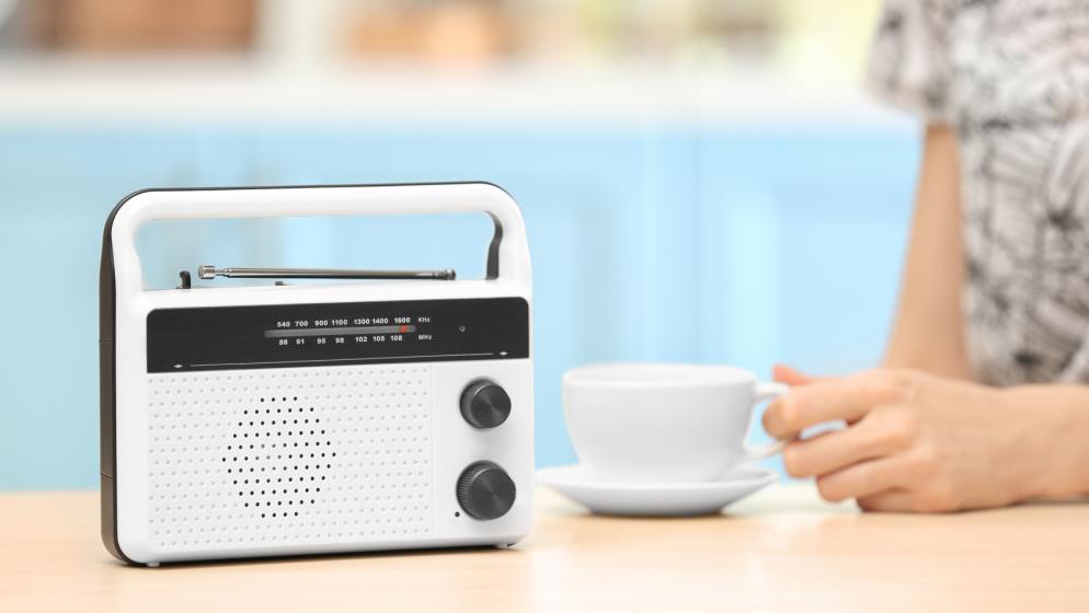 Frau neben Radio und Kaffeetasse