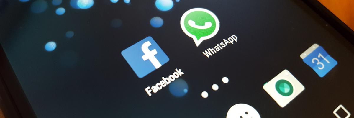 Smartphone mit Logos WhatsApp und Facebook