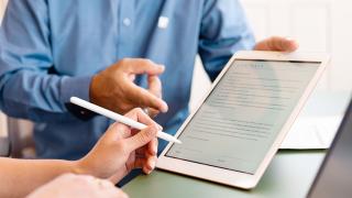 Vertreter reicht einer Frau ein Tablet zur Unterschrift