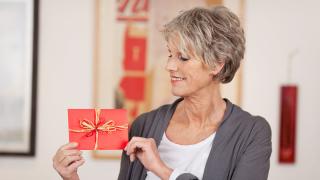 ältere Frau hält einen Geschenkgutschein und lächelt