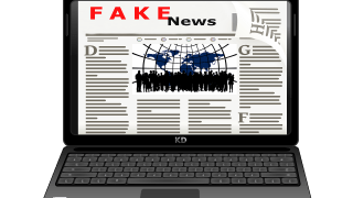 Auf dem Bildschirm eines aufgeklappten Laptops ist das Wort Fake News zu lesen