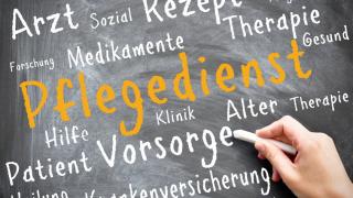 Auf einer Tafel hat jemand das Wort Pflegedienst mit einer Kreide geschrieben