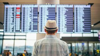 Mann steht vor Anzeigetafel am Flughafen