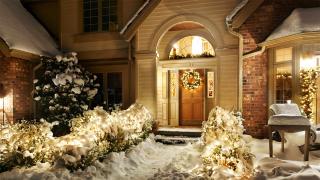 Blick auf mit Weihnachstbeleuchtung geschmückten und verschneiten Hauseingang